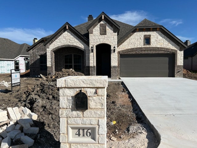 416 Broken Spoke Trl, Waco, TX 76657 - french country home featuring stone siding, an attached garage, driveway, a chimney, and brick siding