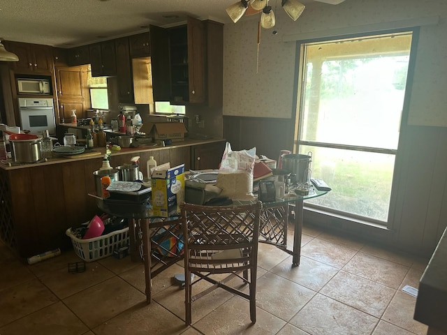3182 E US Highway 84, Palestine, TX 75801 - kitchen with white appliances, wainscoting, light tile patterned flooring, ceiling fan, and a textured ceiling