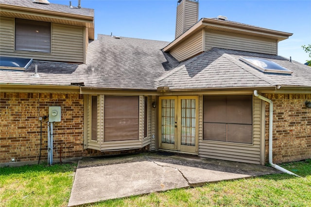 2025 Sancerre Ln, Carrollton, TX 75007 - entrance to property featuring brick siding, a shingled roof, french doors, a chimney, and a patio area