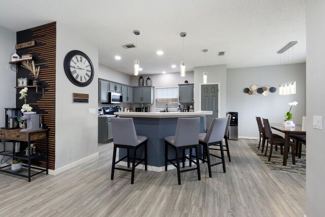 1317 Woodthorpe Dr, Mesquite, TX 75181 - kitchen with light wood-style floors, stainless steel microwave, light countertops, a kitchen bar, and recessed lighting