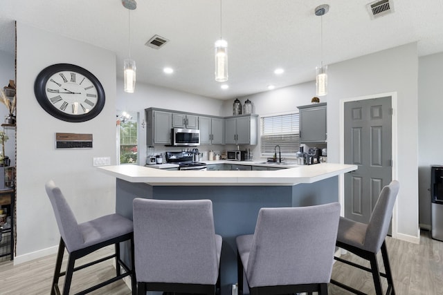 1317 Woodthorpe Dr, Mesquite, TX 75181 - kitchen featuring stainless steel microwave, black range with electric cooktop, gray cabinetry, light wood-type flooring, and light countertops