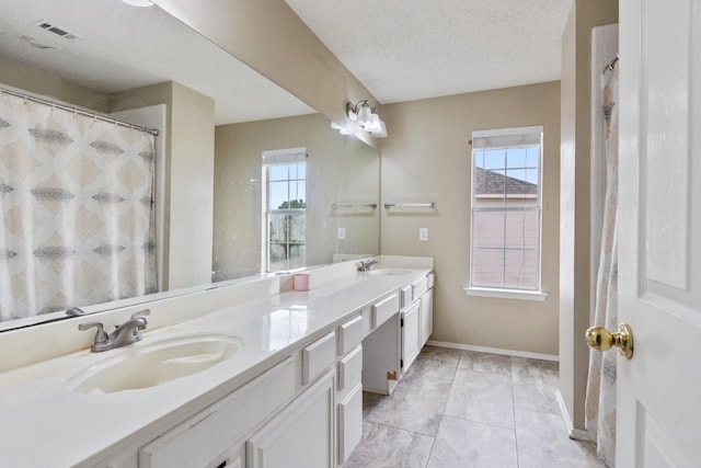 1317 Woodthorpe Dr, Mesquite, TX 75181 - bathroom featuring double vanity, a textured ceiling, and baseboards