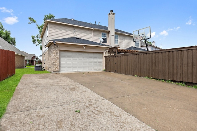 1317 Woodthorpe Dr, Mesquite, TX 75181 - back of property with driveway, central air condition unit, a garage, brick siding, and a chimney