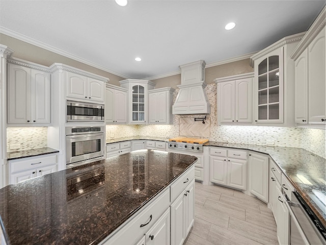 2901 Lakeview Dr, Prosper, TX 75078 - kitchen with stainless steel appliances, premium range hood, crown molding, decorative backsplash, and glass insert cabinets