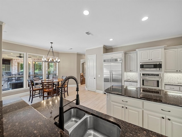 2901 Lakeview Dr, Prosper, TX 75078 - kitchen with built in appliances, hanging light fixtures, white cabinetry, crown molding, and decorative backsplash