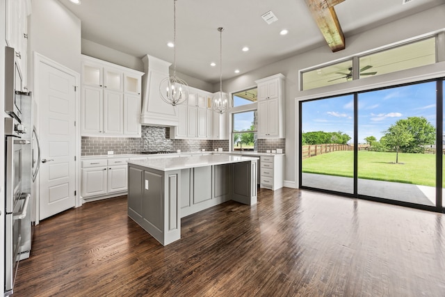 3416 Dovehill Dr, Northlake, TX 76247 - kitchen with a chandelier, a kitchen island, white cabinetry, dark wood-type flooring, and backsplash