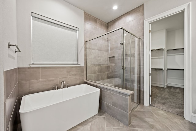 3416 Dovehill Dr, Northlake, TX 76247 - full bathroom featuring a stall shower, a freestanding bath, a spacious closet, recessed lighting, and tile walls