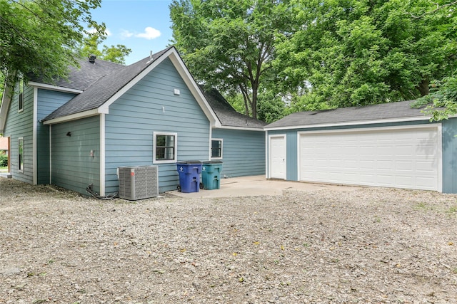 104 W 2nd St, Waxahachie, TX 75165 - view of side of property featuring cooling unit, an outdoor structure, a shingled roof, and a detached garage