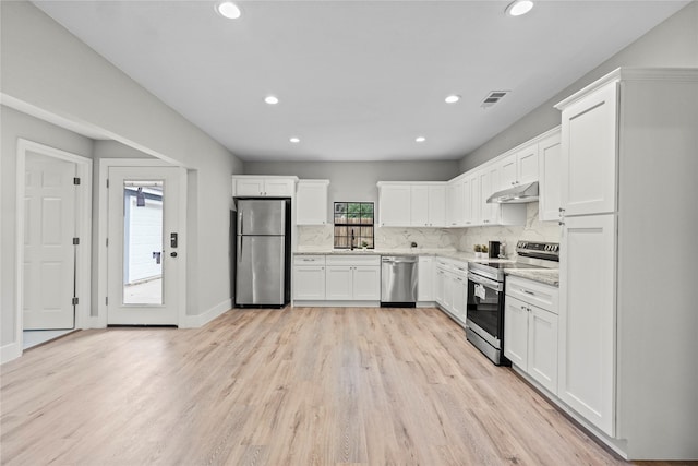 104 W 2nd St, Waxahachie, TX 75165 - kitchen with appliances with stainless steel finishes, under cabinet range hood, a sink, light wood finished floors, and white cabinets