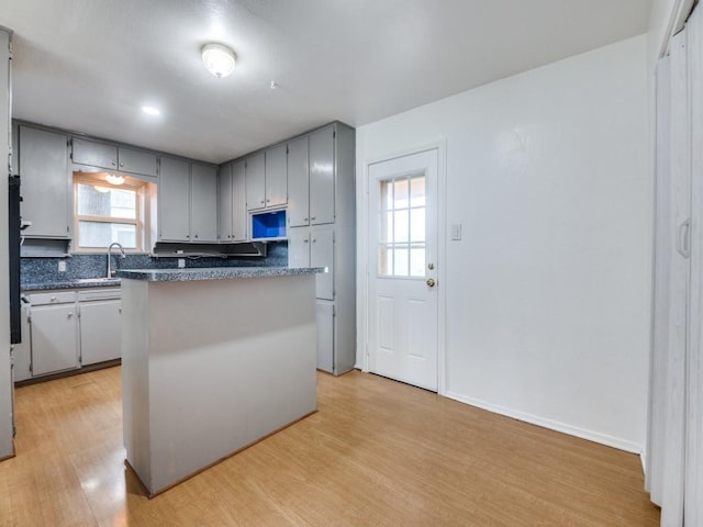 5512 Dennis Ave, Fort Worth, TX 76114 - kitchen with light wood-style floors, dark countertops, a sink, gray cabinetry, and a center island