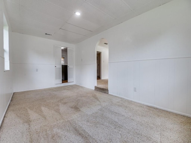 5512 Dennis Ave, Fort Worth, TX 76114 - carpeted empty room with arched walkways, a paneled ceiling, wainscoting, and healthy amount of natural light
