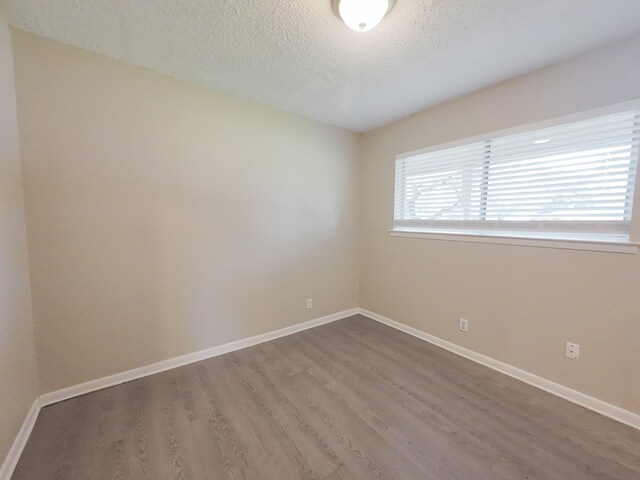 1418 Royal Dr, Kaufman, TX 75142 - empty room featuring a textured ceiling, wood finished floors, and baseboards