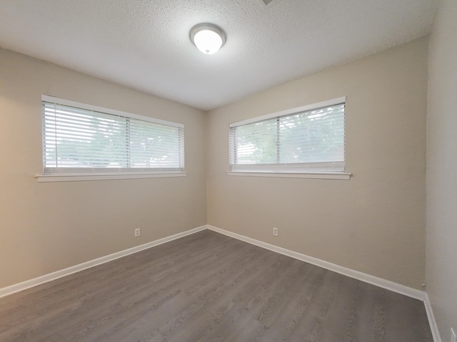 1418 Royal Dr, Kaufman, TX 75142 - empty room with dark wood-style flooring, baseboards, and a textured ceiling