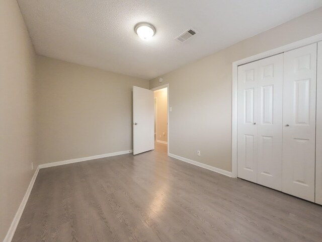 1418 Royal Dr, Kaufman, TX 75142 - unfurnished bedroom featuring wood finished floors, baseboards, a closet, and a textured ceiling