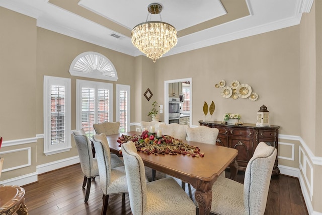 6628 Gray Wolf Dr, Plano, TX 75024 - dining space with a chandelier, dark wood finished floors, ornamental molding, a tray ceiling, and wainscoting