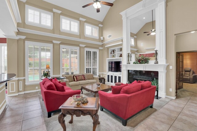 6628 Gray Wolf Dr, Plano, TX 75024 - living area with a ceiling fan, high vaulted ceiling, light tile patterned floors, decorative columns, and a premium fireplace