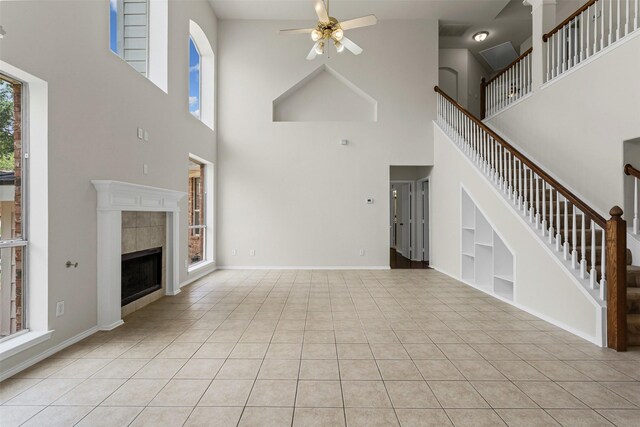 204 Forestview Rd, Hickory Creek, TX 75065 - unfurnished living room with a towering ceiling, a ceiling fan, light tile patterned flooring, a tiled fireplace, and stairway