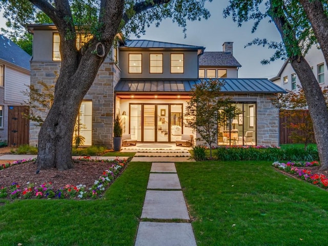 6443 Ellsworth Ave, Dallas, TX 75214 - contemporary home featuring a standing seam roof, stone siding, a chimney, and metal roof