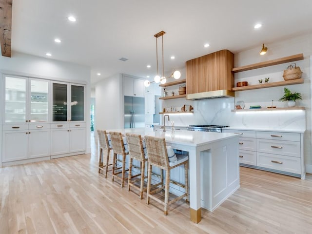 6443 Ellsworth Ave, Dallas, TX 75214 - kitchen featuring open shelves, built in refrigerator, light wood-style flooring, recessed lighting, and a center island with sink