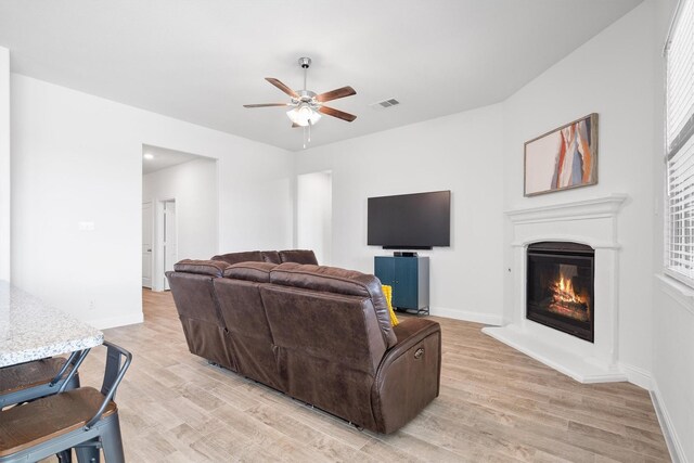 3004 Aransas Ave, Aubrey, TX 76227 - living area with ceiling fan, light wood-style flooring, a glass covered fireplace, and baseboards