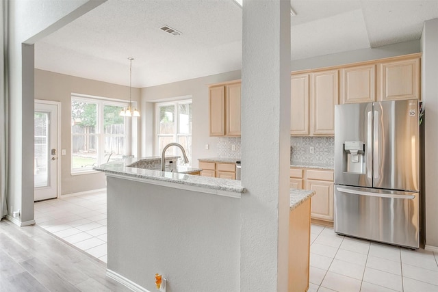 2604 Briarcrest Dr, Burleson, TX 76028 - kitchen featuring stainless steel fridge with ice dispenser, light brown cabinets, a center island with sink, a sink, and light stone counters