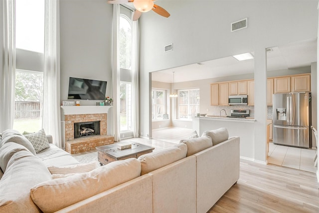 2604 Briarcrest Dr, Burleson, TX 76028 - living room with a towering ceiling, a ceiling fan, light wood-type flooring, and a fireplace with raised hearth
