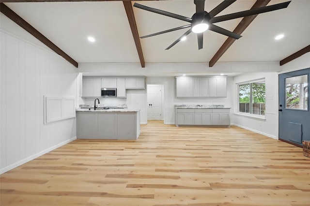 9813 Bancroft Dr, Benbrook, TX 76126 - kitchen with stainless steel microwave, beam ceiling, a peninsula, light wood-style floors, and baseboards
