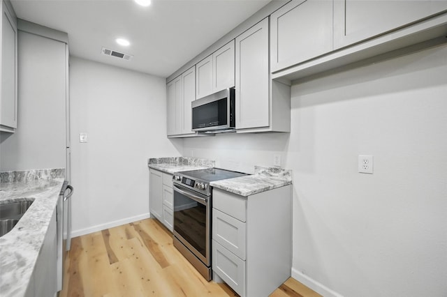 9813 Bancroft Dr, Benbrook, TX 76126 - kitchen with stainless steel appliances, baseboards, light wood-style flooring, gray cabinets, and recessed lighting