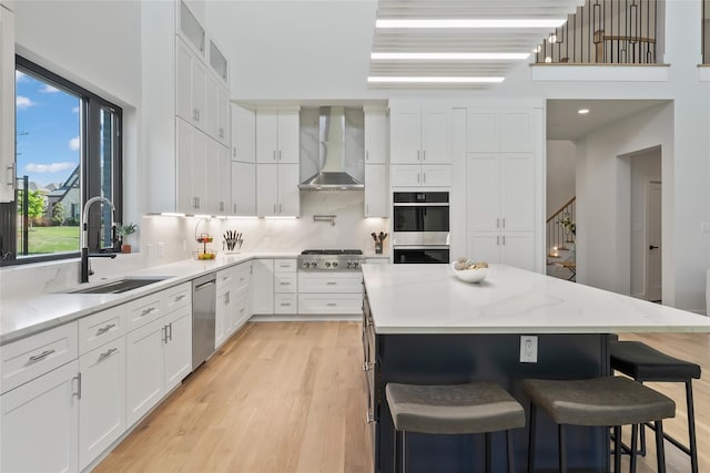 1209 Hicks Trl, Lucas, TX 75002 - kitchen featuring wall chimney exhaust hood, a sink, appliances with stainless steel finishes, a breakfast bar, and white cabinets