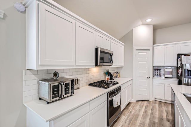 1211 Caddo Hill Ct, Royse City, TX 75189 - kitchen featuring stainless steel appliances, tasteful backsplash, white cabinetry, vaulted ceiling, and light wood-style flooring