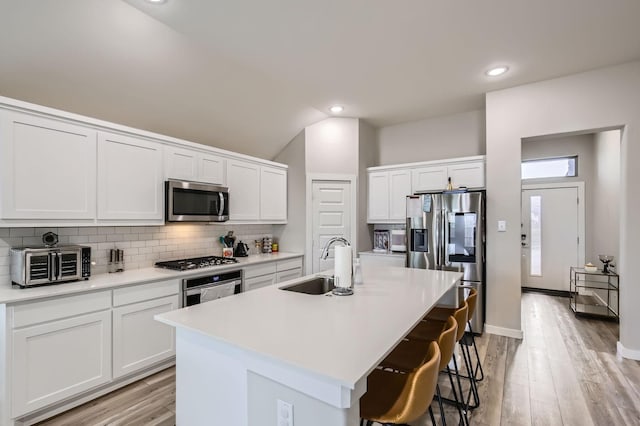 1211 Caddo Hill Ct, Royse City, TX 75189 - kitchen featuring appliances with stainless steel finishes, a sink, tasteful backsplash, a breakfast bar area, and white cabinetry