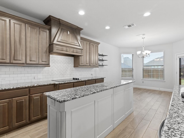 2508 Bunker Hill Dr, Burleson, TX 76028 - kitchen with premium range hood, black electric cooktop, a chandelier, decorative backsplash, and pendant lighting