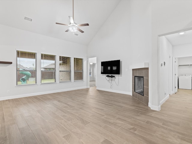 2508 Bunker Hill Dr, Burleson, TX 76028 - unfurnished living room featuring washer / clothes dryer, high vaulted ceiling, ceiling fan, light wood finished floors, and a tile fireplace