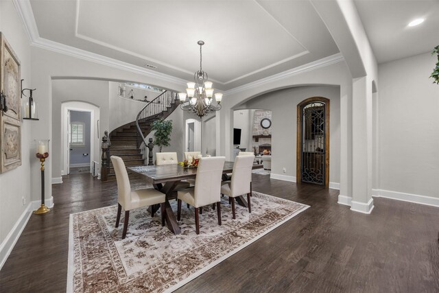 8249 Treemont Pl, Frisco, TX 75034 - dining room with a raised ceiling, stairway, dark wood-style flooring, baseboards, and arched walkways