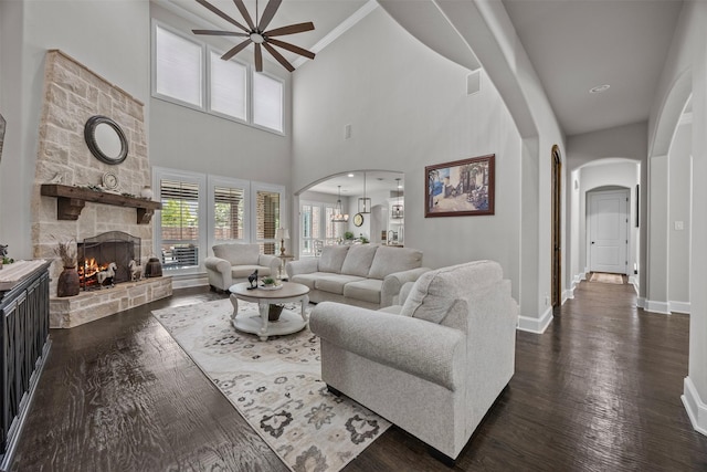8249 Treemont Pl, Frisco, TX 75034 - living area featuring arched walkways, ceiling fan, a fireplace, baseboards, and dark wood finished floors