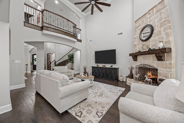 8249 Treemont Pl, Frisco, TX 75034 - living room featuring a stone fireplace, ceiling fan, arched walkways, stairway, and baseboards