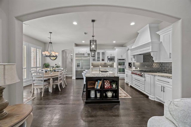 8249 Treemont Pl, Frisco, TX 75034 - kitchen with built in appliances, a sink, white cabinets, arched walkways, and recessed lighting