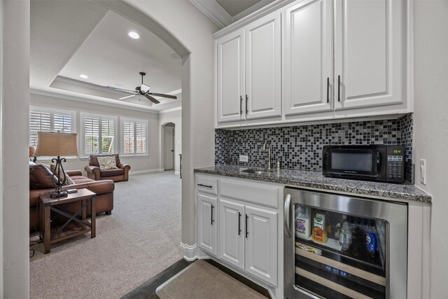 8249 Treemont Pl, Frisco, TX 75034 - bar with arched walkways, wine cooler, black microwave, crown molding, and a ceiling fan