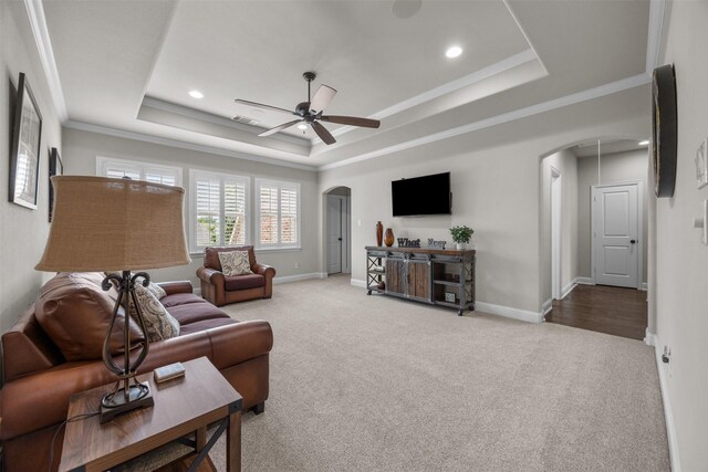 8249 Treemont Pl, Frisco, TX 75034 - living area featuring arched walkways, carpet, a tray ceiling, ceiling fan, and crown molding