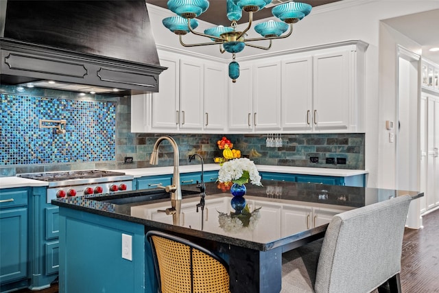 7905 Strathmill Dr, The Colony, TX 75056 - kitchen featuring exhaust hood, blue cabinets, stainless steel gas stovetop, and decorative backsplash