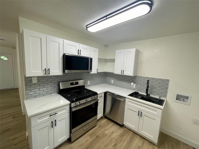 126 Stephens St, Waxahachie, TX 75165 - kitchen with appliances with stainless steel finishes, a sink, white cabinets, decorative backsplash, and light wood-type flooring