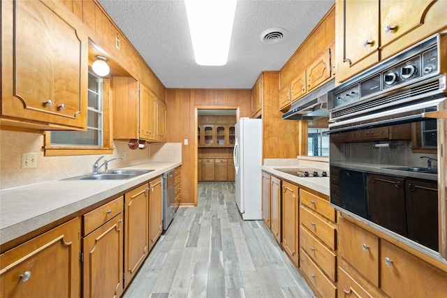 201 Palestine St, Coleman, TX 76834 - kitchen featuring a sink, black appliances, light wood-type flooring, brown cabinetry, and a textured ceiling
