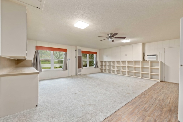 201 Palestine St, Coleman, TX 76834 - unfurnished living room featuring a ceiling fan, a textured ceiling, a wall mounted AC, and light wood-type flooring