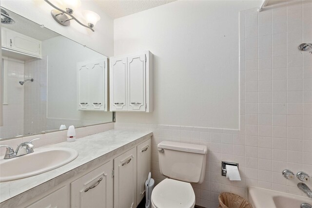 201 Palestine St, Coleman, TX 76834 - bathroom featuring vanity, toilet, wainscoting, tile walls, and a textured ceiling
