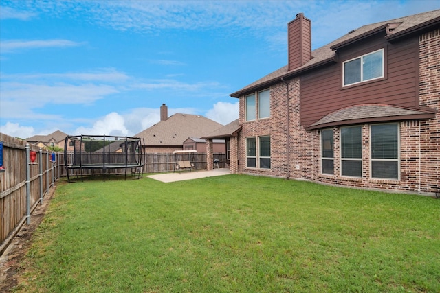 3302 Blue Jay Ln, Melissa, TX 75454 - back of house featuring a trampoline, a patio area, brick siding, a chimney, and roof with shingles