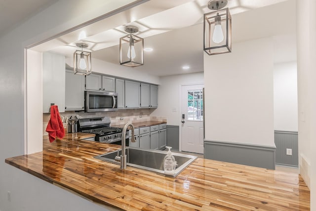 1503 County Road 705, Joshua, TX 76058 - kitchen featuring stainless steel appliances, gray cabinets, a sink, wood finished floors, and backsplash