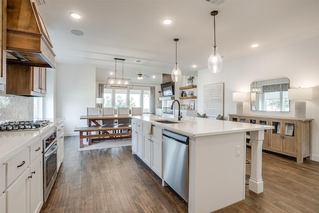 9925 Chaparral Pass, Fort Worth, TX 76126 - kitchen featuring appliances with stainless steel finishes, dark wood-type flooring, light countertops, a kitchen island with sink, and decorative light fixtures