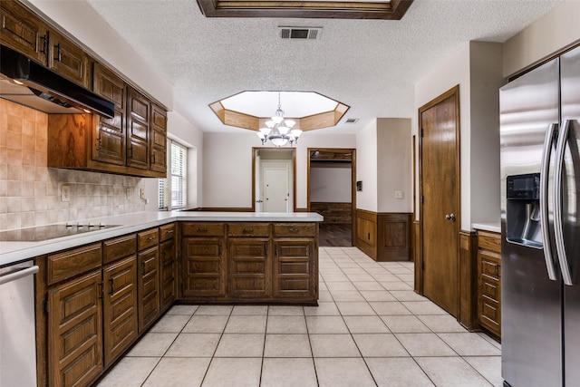 1504 Huron Trl, Plano, TX 75075 - kitchen featuring appliances with stainless steel finishes, light countertops, a wainscoted wall, a textured ceiling, and under cabinet range hood