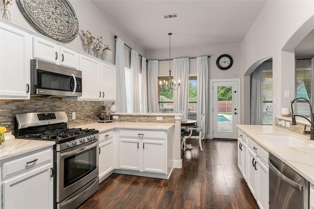 3659 Smoketree Dr, Rockwall, TX 75032 - kitchen featuring appliances with stainless steel finishes, a chandelier, arched walkways, a peninsula, and decorative backsplash