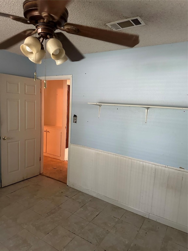 2410 Asbury St, Brownwood, TX 76801 - empty room with wainscoting, ceiling fan, a textured ceiling, and wooden walls